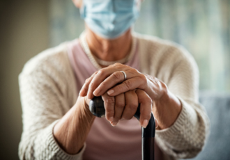 Person holding walking stick with face mask on